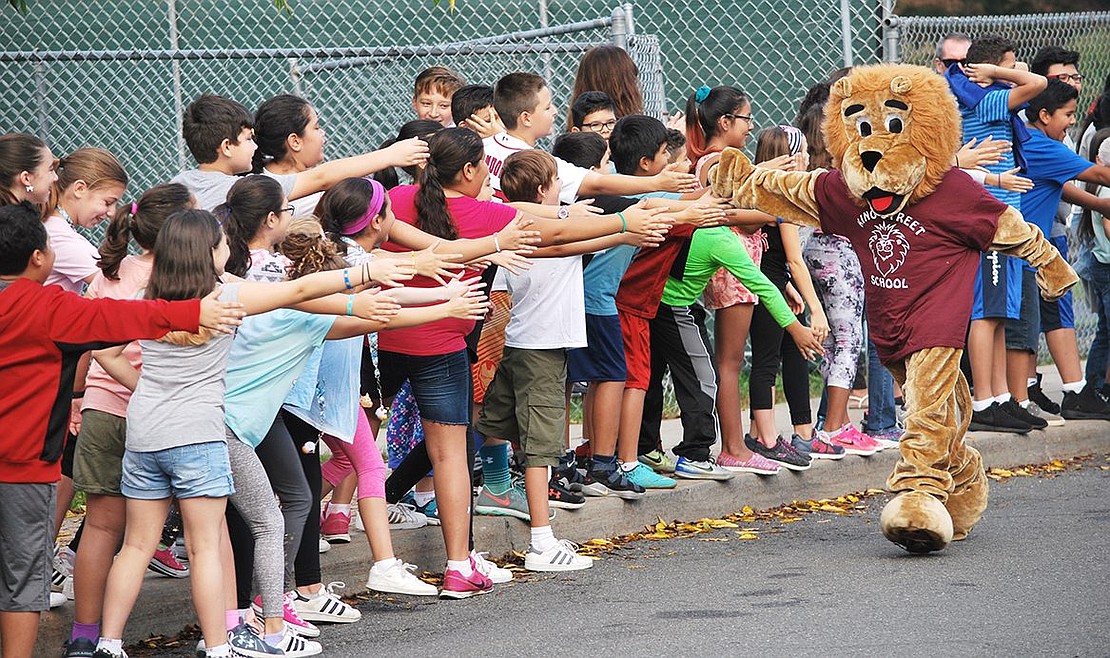 Roary the King Street School mascot, played by alumnus Noah Rotfeld, now a ninth grader at Port Chester High School, high fives enthusiastic students after arriving at the school via a Brooksville Engine & Hose fire truck.