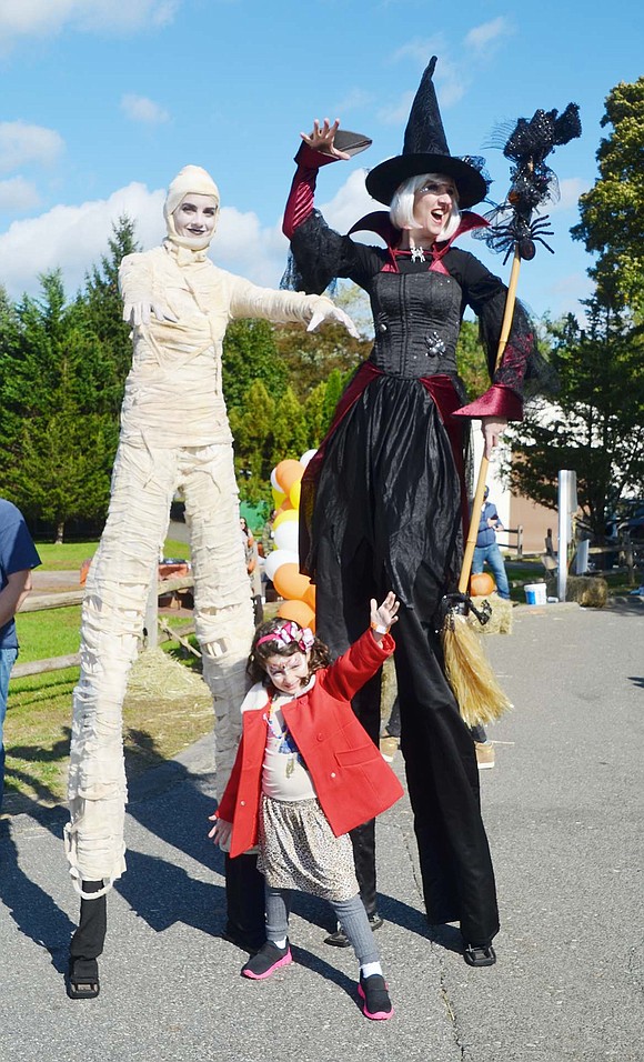 Beneath blue skies and scary monsters, Ridge Street Elementary School kindergartener Laura Malzyner hangs out with her new spooky friends at the fifth annual PTA-sponsored Blind Brook Fall Fest at the elementary school on Saturday, Oct. 20. The Bayberry Lane resident is towered by Cirque du Jour performers Tanya Turngeon (the mummy) and Erin Grins (the witch).