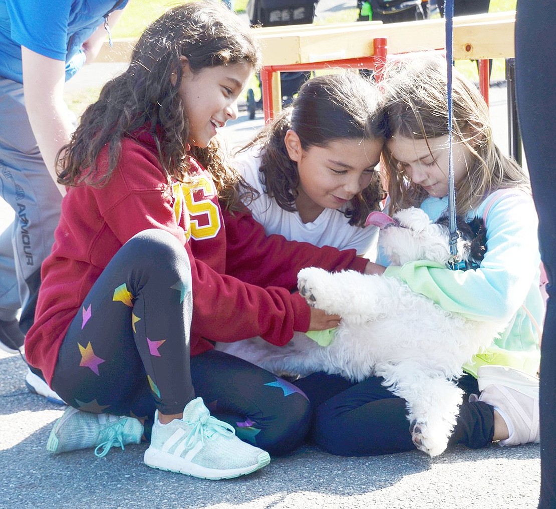 Ridge Street Elementary School fourth-graders Camila Gonzalez (left), Lyla Cotte and Carlee Gabriel take a moment for some puppy love with Tyler Copland, an 8-month-old cockapoo. 