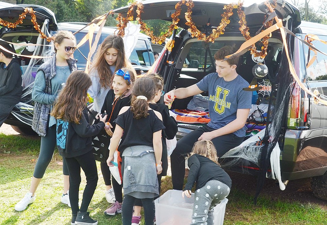Blind Brook High School freshman and Windingwood Road resident Mark Short sits in the back of a Halloween-decorated SUV and passes out candy to a group of “Trunk or Treating” kids.