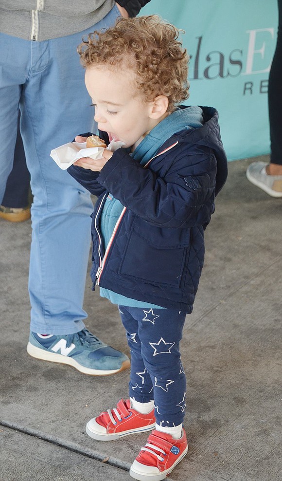 While his dad chats with friends, 3-year-old Dobbs Ferry resident Wyeth Galen busies himself with a giant bite of a sugary doughnut. 