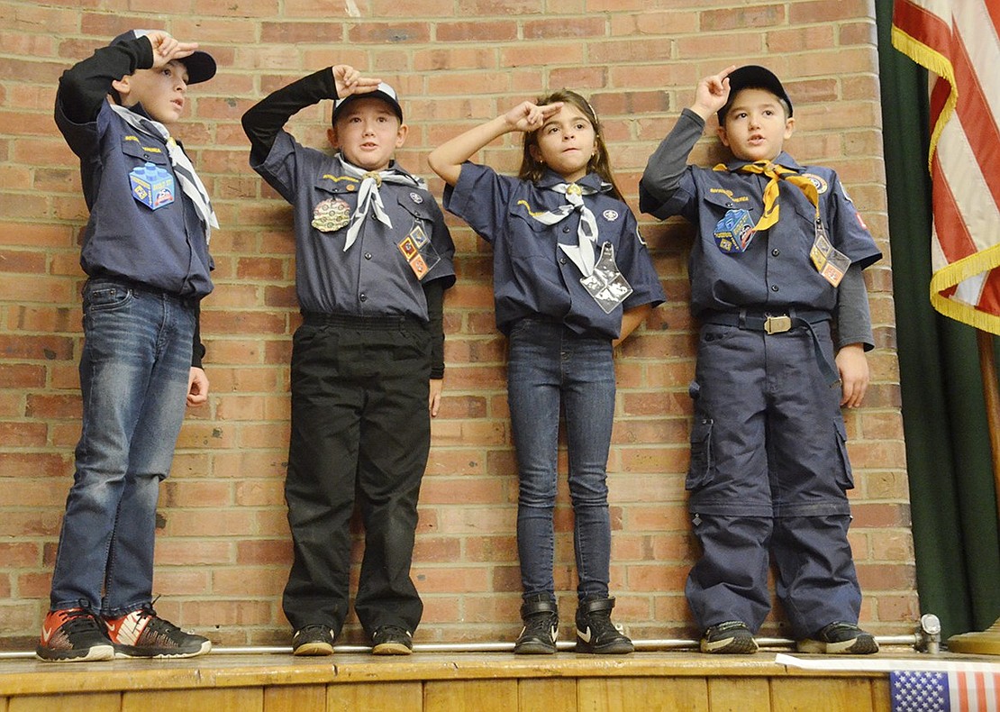 Four Cub Scouts salute the American flag and lead the King Street Elementary School auditorium filled with third- through fifth-graders and officials in the Pledge of Allegiance during the Veterans Day ceremony at King Street School on Friday, Nov. 9. From the left: third-grader Gavin Stone, third-grader Evin Eski, third-grader Sophia Faraci and second-grader Santo Giordano.