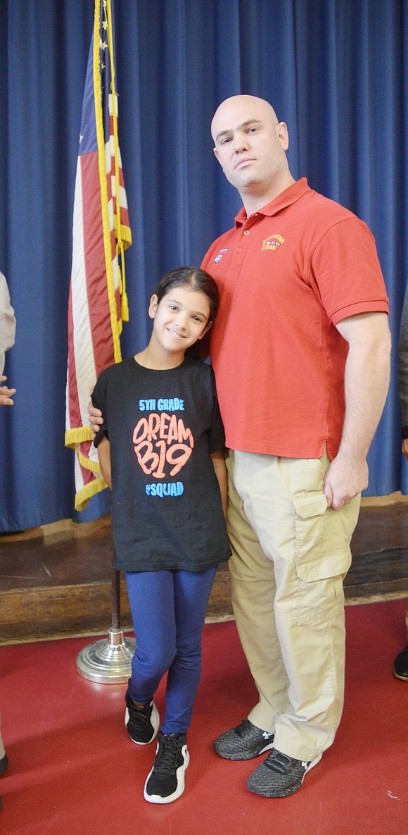 Afghanistan veteran Mark Trezza proudly stands with his fifth-grade daughter Emily by the American flag after the Park Avenue School ceremony. 