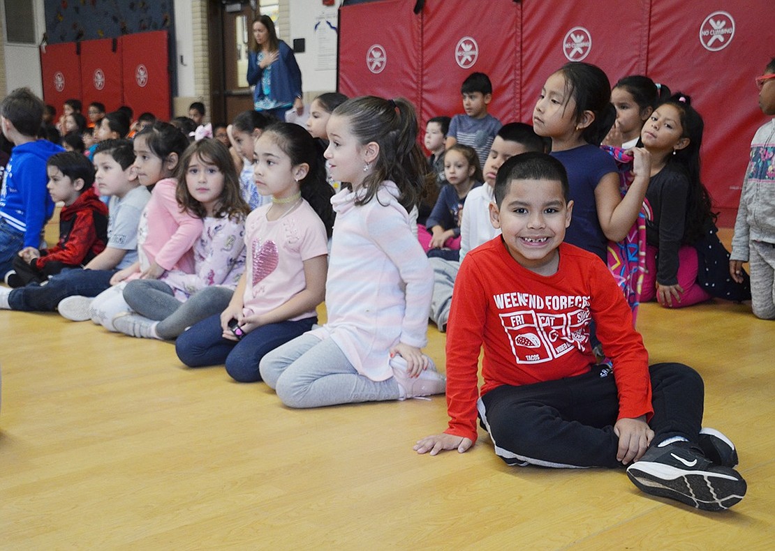 As Park Avenue School students sit in a single file to listen to speakers, first-grader Juan Molina briefly breaks formation to smile for the camera.