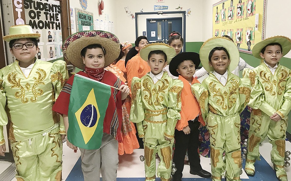 Fourth-grader Joaquin Silveira waves the Brazilian flag as he and several other sharply dressed Edison School students gather in the school’s hallway. Courtesy of Carolee Brakewood 