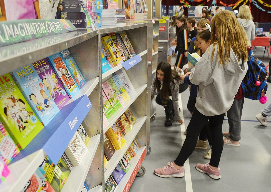 A line of fourth-graders choose and peruse various magical books for sale at the Scholastic Enchanted Forest Book Fair in the Ridge Street Elementary School gymnasium on Tuesday, Nov. 13. Some proceeds from the week-long book sale benefit the school’s PTA every year.