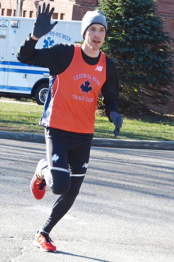 Phil Falk of New York City waves as he crosses the finish line to complete the 3.5-kilometer fun run first for the second year in a row. His brother Abraham lives in Port Chester. He didn’t clock his time but said he’s in better shape so ran faster than last year despite the bitter cold.