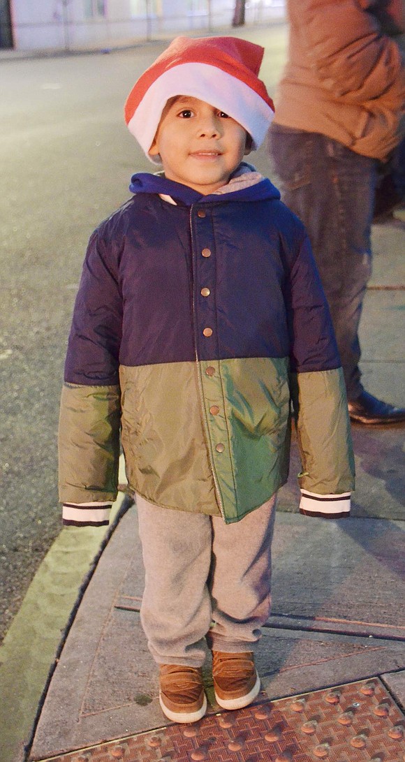 Adorned with a jolly oversized Santa hat, 4-year-old Sebastian Martinez of Port Chester eagerly awaits the procession at the corner of Highland Street and Abendroth Avenue.