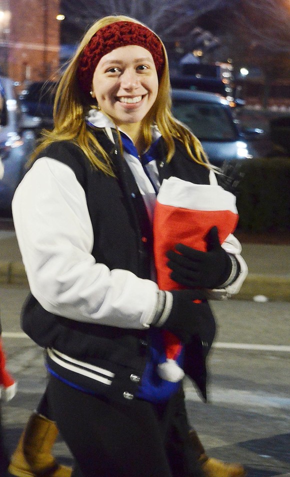 Clutching a Santa hat filled with candy, Port Chester High School senior Carolyne Molano marches with the Port Chester High School varsity cheerleading squad, ready to toss treats to children lining the road.