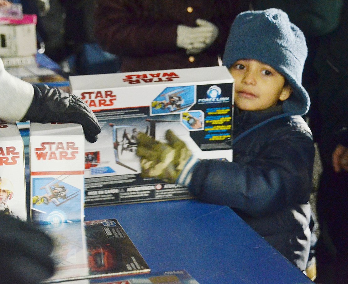 As he affectionately hugs his new Star Wars spaceship, it looks like King Street Elementary School kindergartener Bryan Lopez found the perfect toy at the gift table.