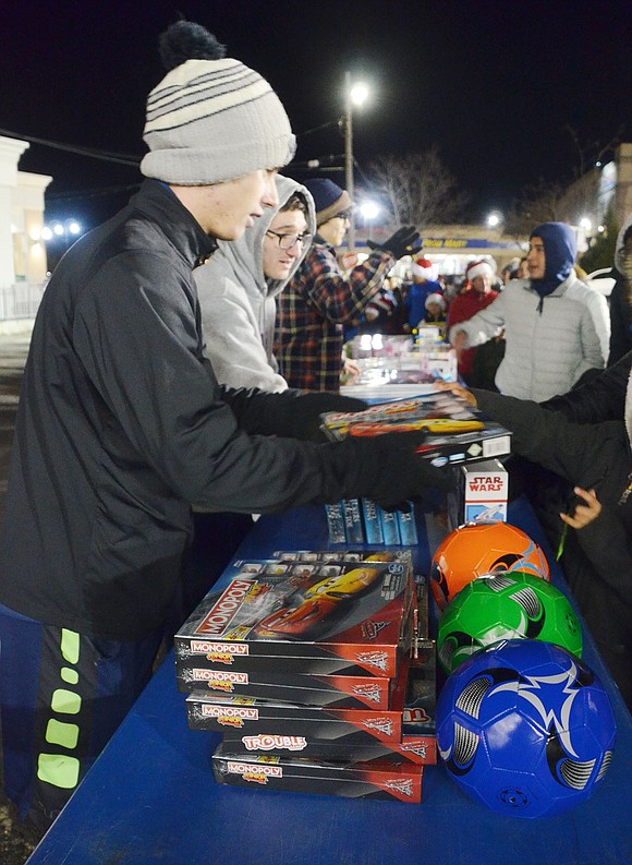 Port Chester High School junior Michael Kessler works with four other students to organize and stock the gift table while helping children pick out presents provided by the Port Chester Recreation Department. The high schoolers are volunteering with the Key Club.