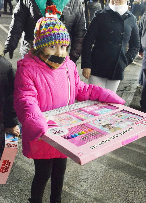 The cold is worth it when Santa’s involved. John F. Kennedy second-grader Melani Zuniga made sure to bundle up tight in her scarf and bright pink coat before coming out to pick a similarly pink Ultimate Stationery Set present and meet Santa.