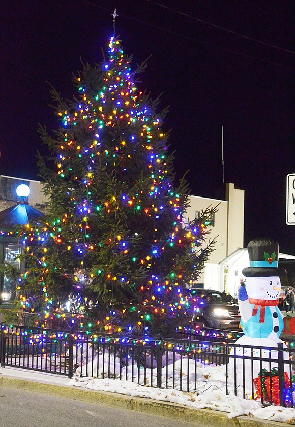 A snowman waves at passersby in front of the towering festive Christmas tree in Liberty Square.