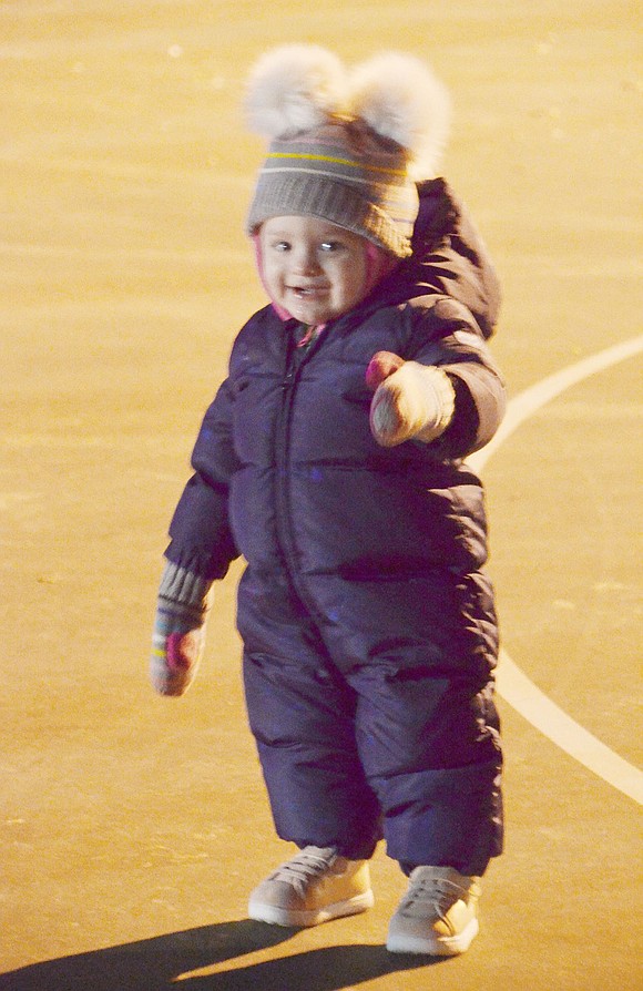 Though a harsh winter chill runs rampant throughout the festival, 16-month-old Rye Brook resident Hudson Lefkowitz feels fine as she’s bundled up in her older brother’s snowsuit.