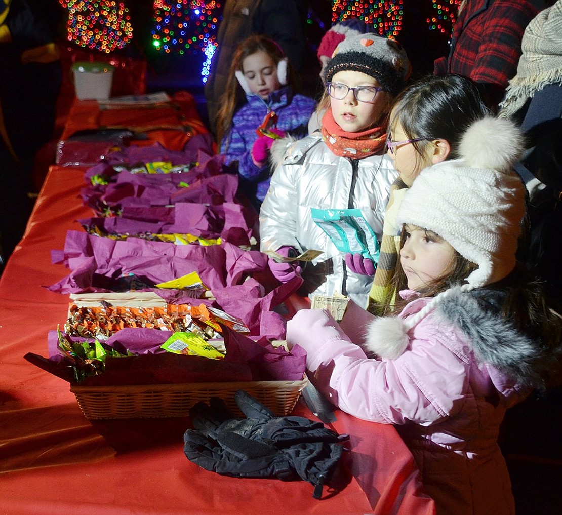 As they anxiously wait for popcorn to warm them up, Ridge Street Elementary School first-grader Valentina Pardinas (front) and fourth-graders Nanami Fujisawa and Aline Vandergoten stand at the snack table with money in hand.