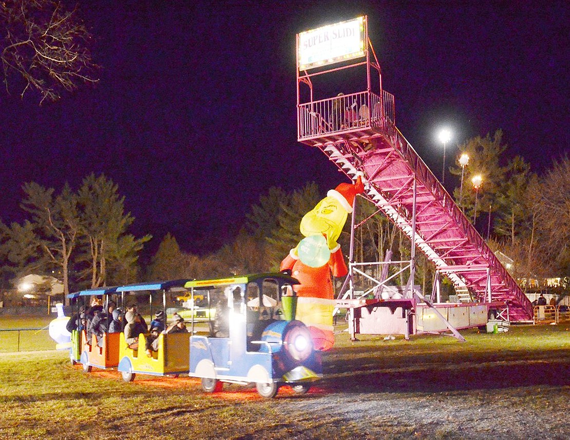 During its loop around Pine Ridge Park, the polar express train filled with children chugs away in front of the towering Super Slide and inflatable Grinch decoration welcoming guests to Winterfest.