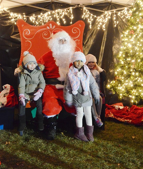 Ridge Street Elementary School kindergarteners Audrey Peña (left), Charlotte Sundheim and Shannon Murphy politely pose for a picture before eagerly crowding around Santa (played by John Giordano) to chat about presents.