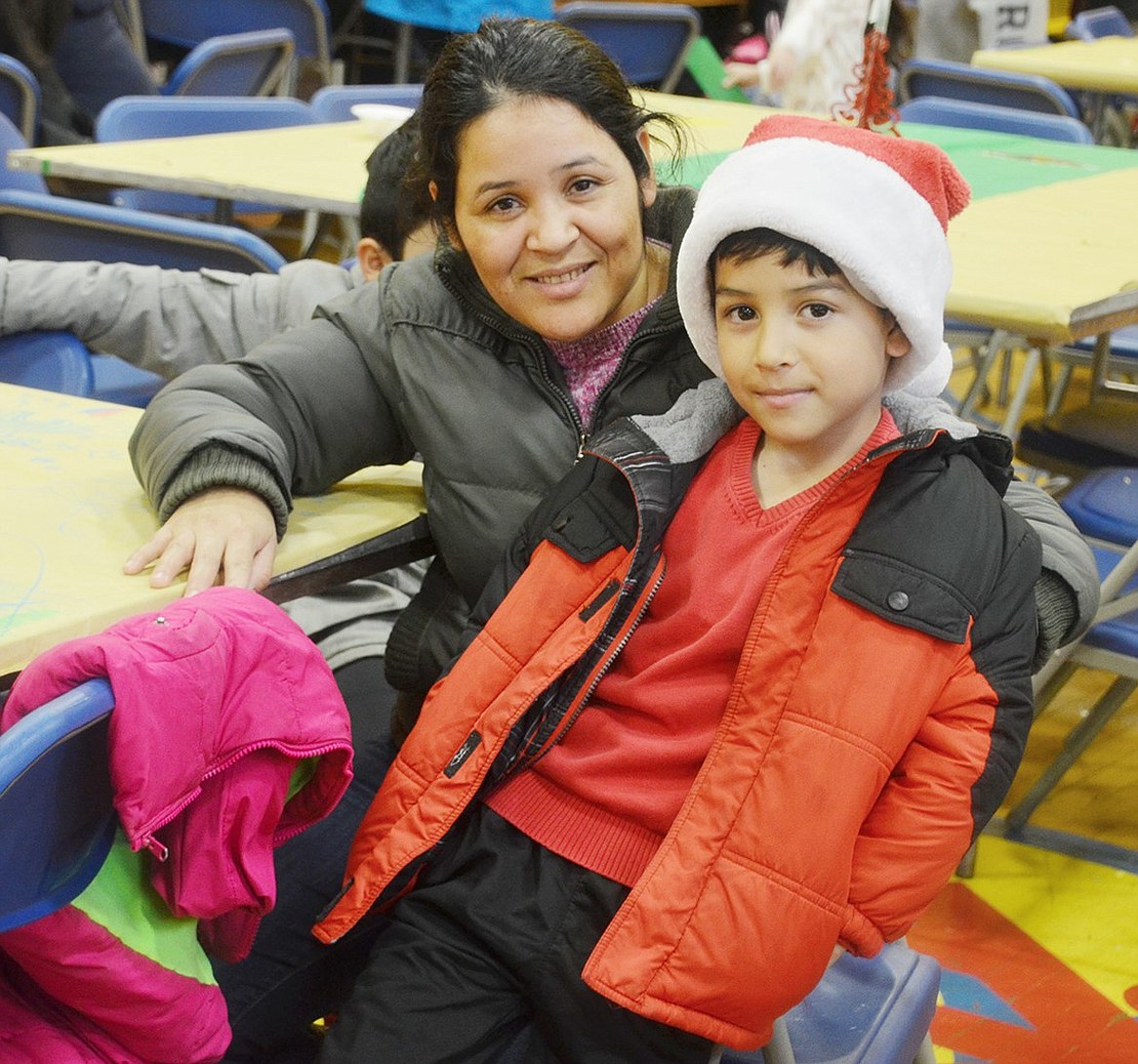 Eager for his row of tables to be called up for the Santa line, John F. Kennedy Elementary School second-grader James Rodriguez waits patiently with his mother Milvia.