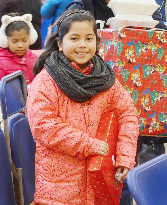 Clutching her bright red present, John F. Kennedy fifth-grader Aracely Sanchez can’t wait to find out what Santa gave her for Christmas this year.