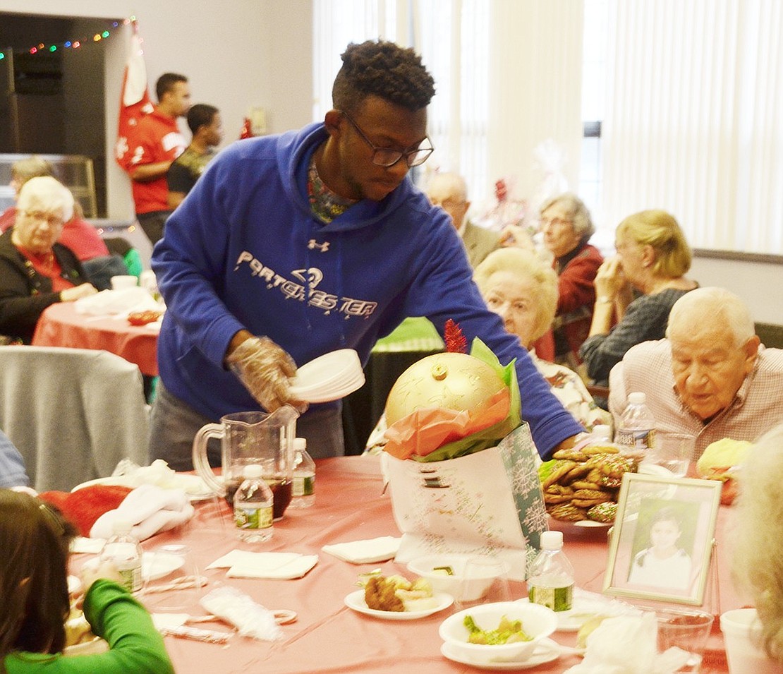 Volunteering with a half dozen others from the Carver Center, 15-year-old Purdy Avenue resident Cameron Burnett delivers a heaping tray of cookies to one of the tables.