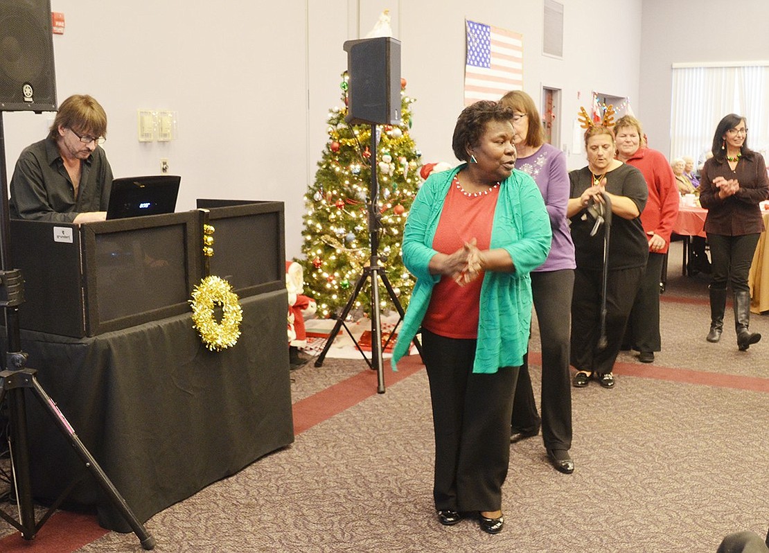 Fairview Place resident Martha Bell leads a group of partygoers in the “Electric Slide” in front of the DJ booth and festive Christmas tree.