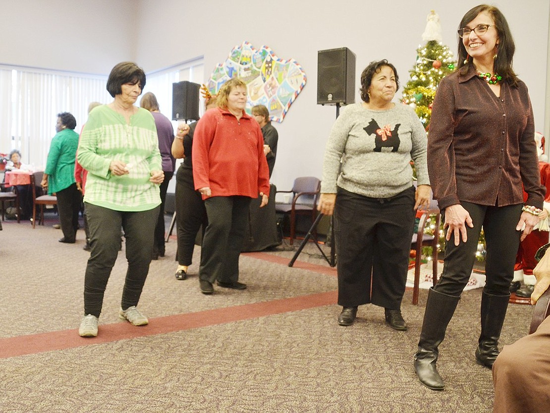 Senior Center members aren’t the only ones getting into the holiday fun. As a guest of her mother-in-law, Tower Hill Drive resident Marianne Luchetta dances at the end of a line of others doing the “Cha-Cha Slide.”