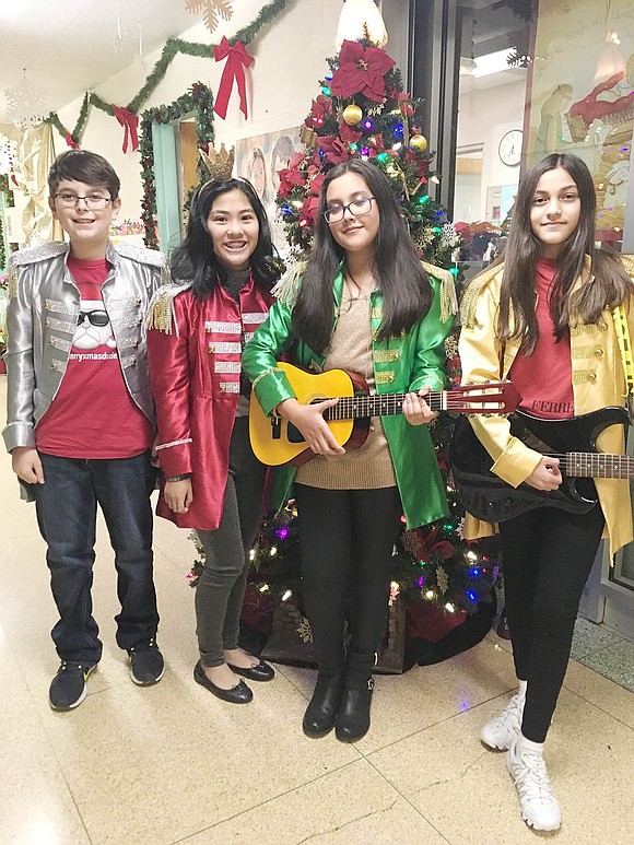 After going onstage to play the Wise Guys rock band, Daniel DeLeo (left), Jemarose Gonzalez, Sara Martinez and Romina Tarnovsky pose for a picture by the Christmas tree in the school’s hallway. Courtesy of Kathy Zaccagnino 