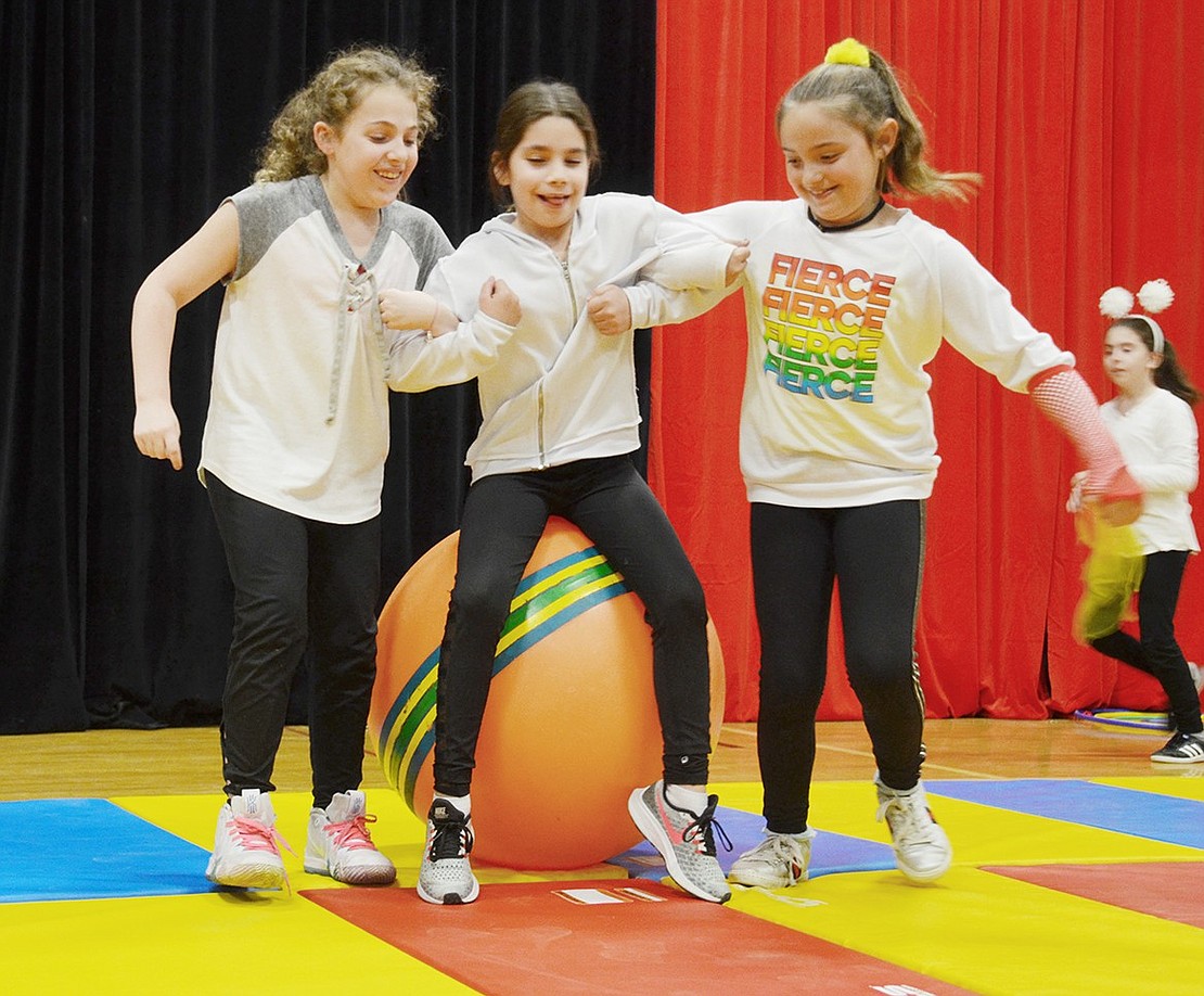 What’s a circus without the clowns? During a silly between act routine, fourth-grade clowns Madison Hamlet (left) and Sara Levine (right) start to carry Ella Rackenberg off a large orange yoga ball.