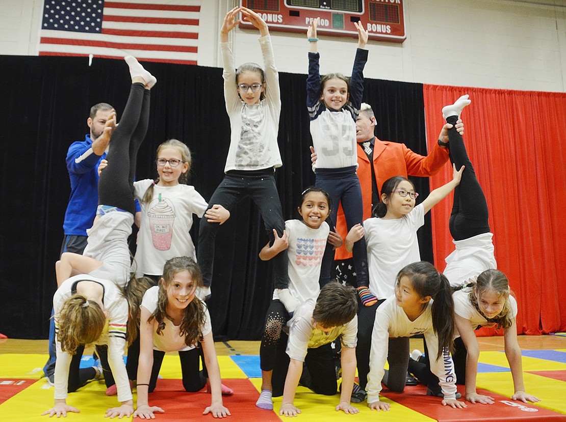 A dozen fourth-graders turned gymnastic experts create a pyramid together as a final pose to their act.