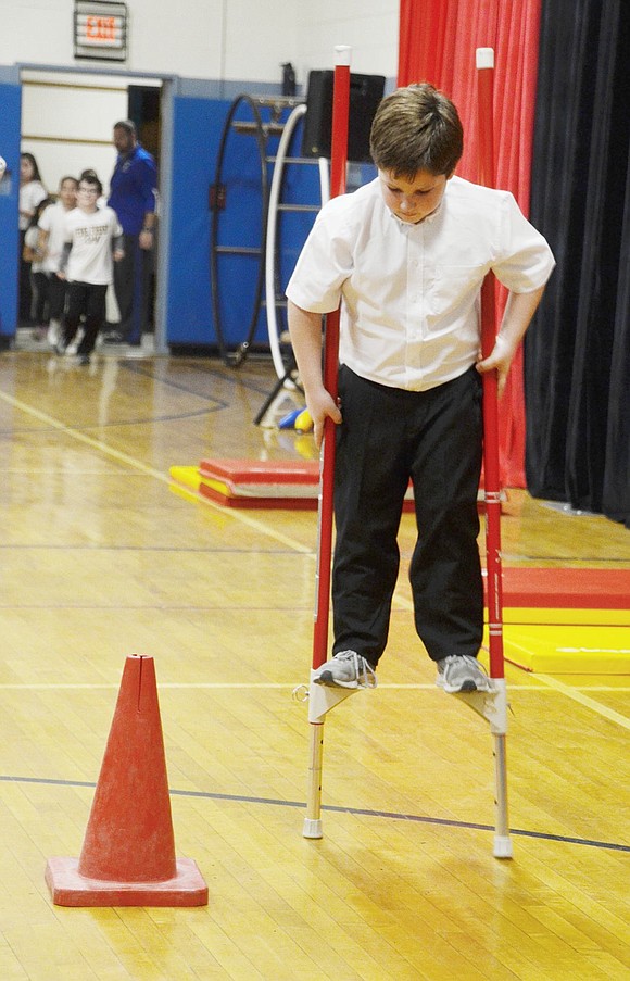 With extreme focus on the obstacle, Joshua Simkin shows off his newfound elevated talent by walking around a red cone on stilts.