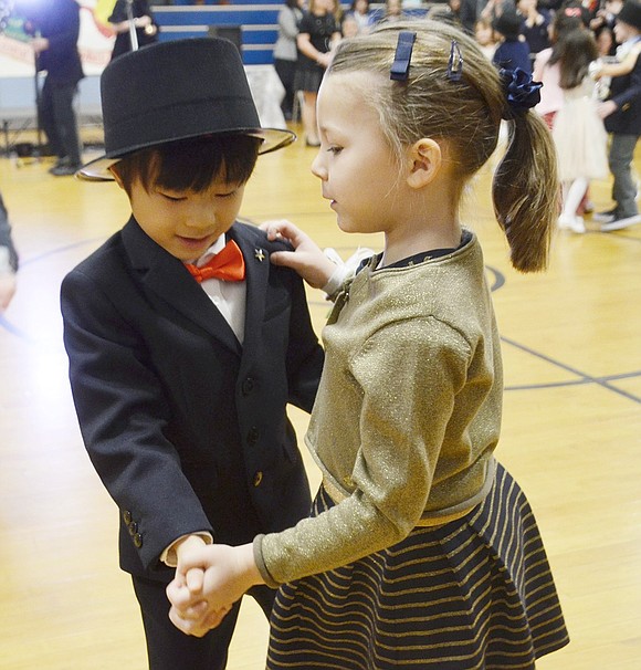 Ridge Street Elementary School first-graders Hiroyoshi Wada and Isabelle Hamladji Ambrosio’s hands embrace as they gracefully dance to “Winter Wonderland” during the annual first-grade Snowball on Friday, Jan. 18. 