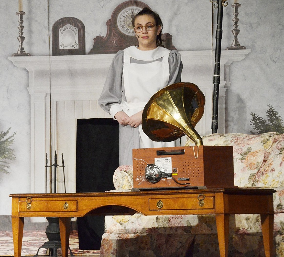 Mrs. Brill, played by Caroline Policarpo, organizes the Banks family heirlooms in their living room.