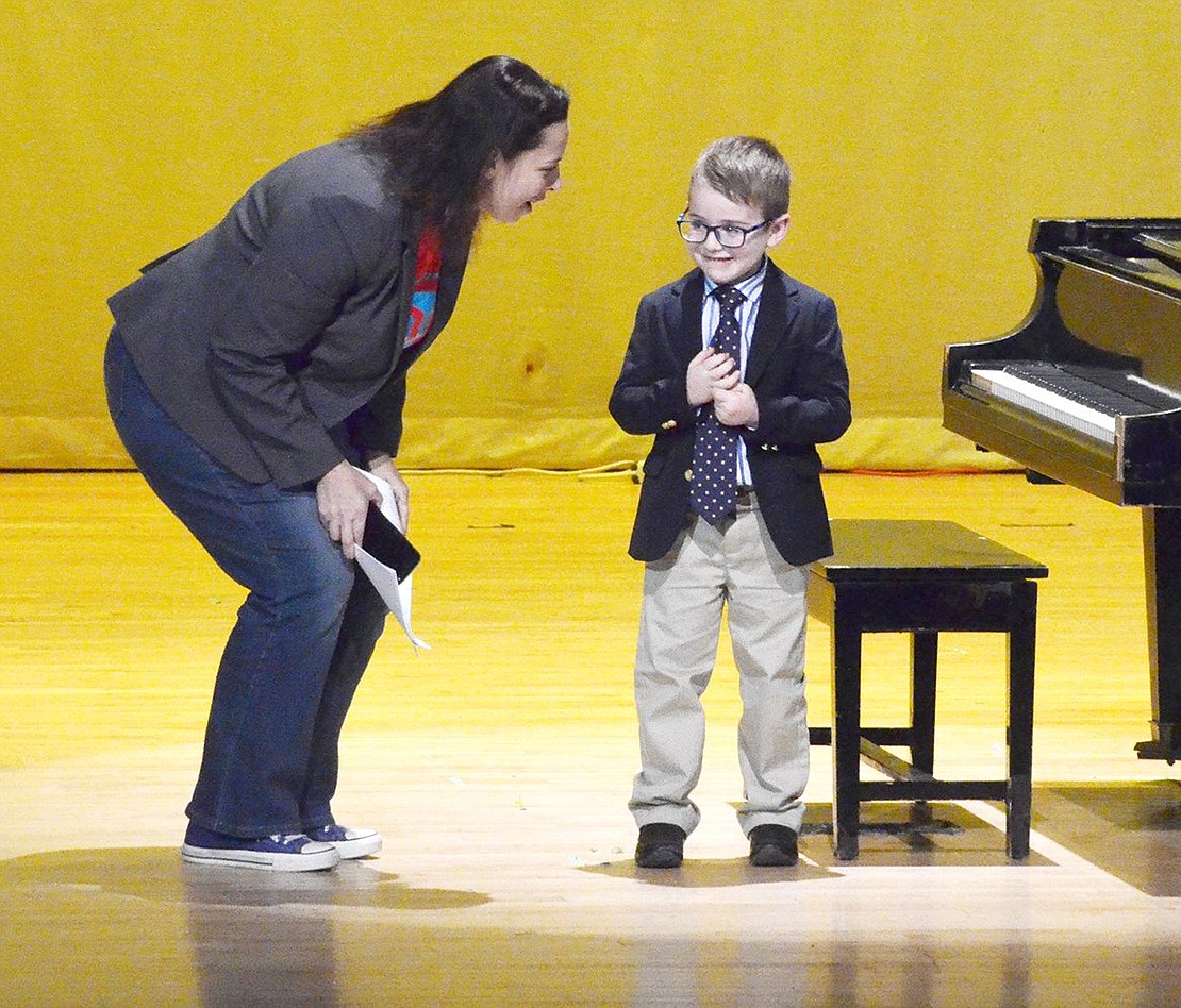 Emcee and Ridge Street Elementary School Principal Tracy Taylor coaxes shy kindergartener David Gitkind into taking a bow for the packed auditorium after his piano solo.
