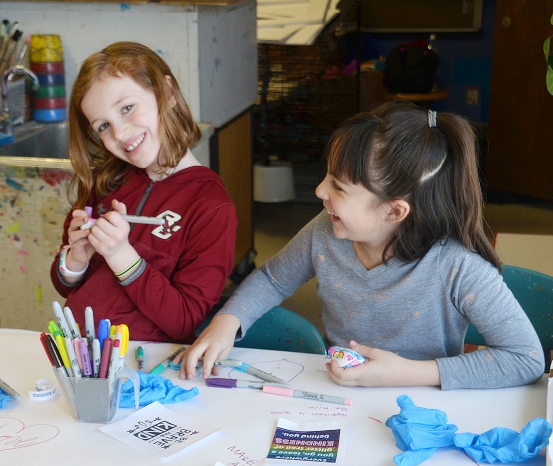 Annabelle Moore (left) and Ana Mattinson giggle together as they put colorful finishing touches on their stones.