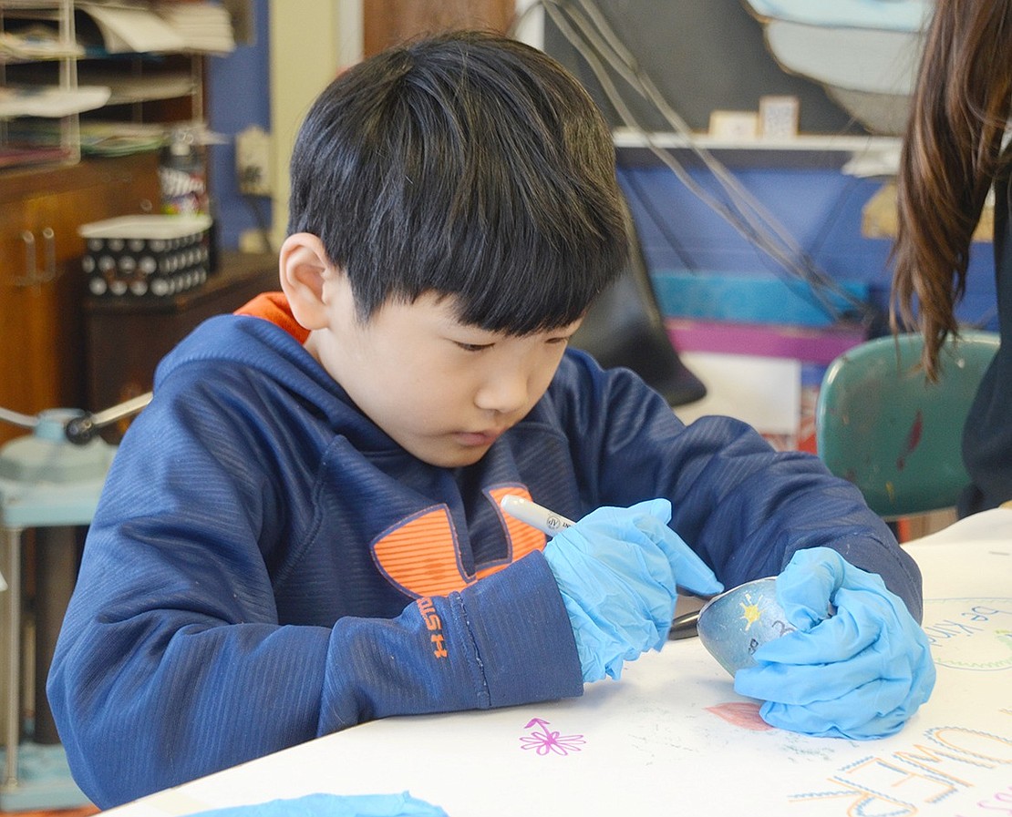 While wearing gloves so the Sharpies don’t stain his hands, Isaac Held carefully decorates his rock with smooth, graceful lines of blue.