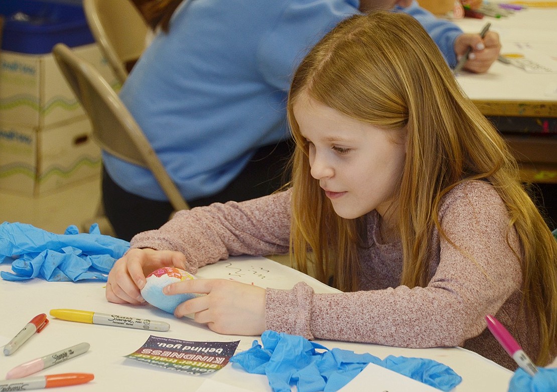 Daria Ivanova gently smiles at the kind messages she wrote on her rock. After all the stones are water treated, Ridge Street art teacher Betsy Murphy said they will use them to make a rock garden at the front entrance of the school.