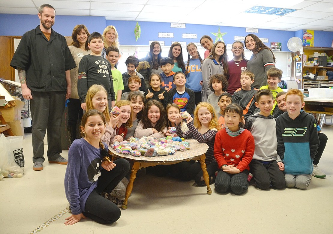 At the end of the class period, the third-graders in Daniel Sottile’s class, visiting Blind Brook High School students and the affiliated teachers pose for a photo around their table stacked with kindness rocks.