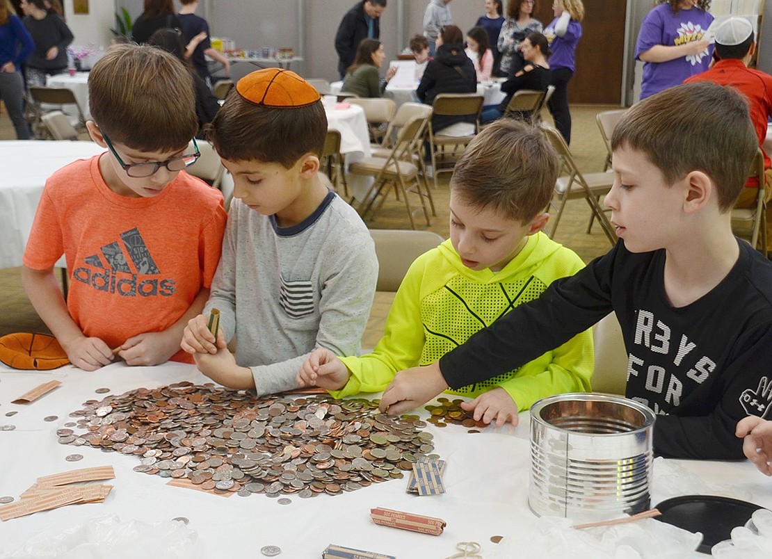 Ridge Street Elementary School second-graders Sammy Samuels (left), Leon Samuels, Zach Capon and Bryce Hudesman swarm a table to wrap change for Mazon, a non-profit focused on hunger and food insecurity. Coin rolling was the most popular activity at this year’s Mitzvah Madness! at Congregation KTI in Port Chester on Sunday, Mar. 24.