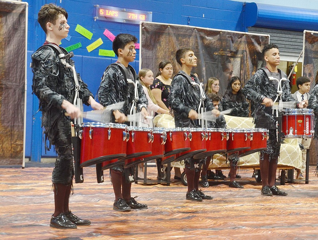 Standing with discipline at the edge of the group, junior Anthony Cortese plays the quads as the drumline demonstrates their warmup exercises.