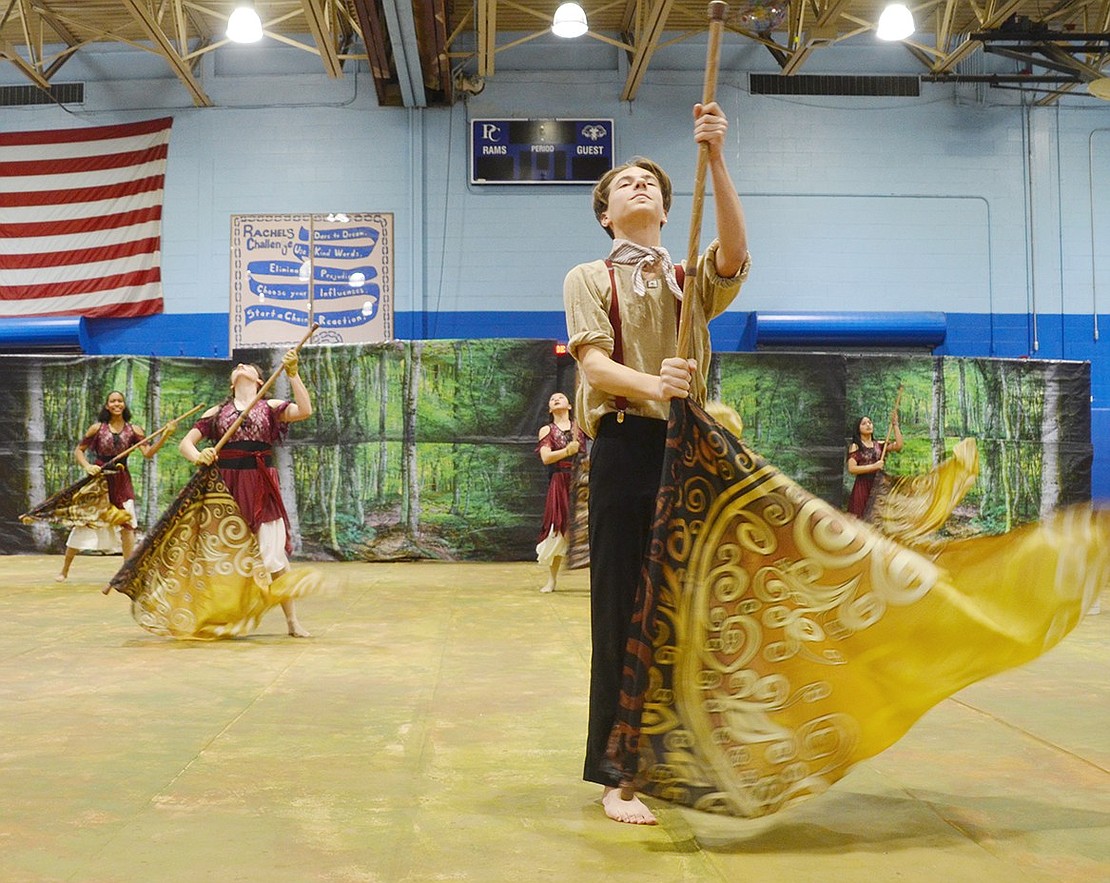 Ahead of other coordinated color guard dancers and a whimsical forest backdrop, freshman John Ceruzzi strikes an elegant pose. The flag yielding Winter Guard members are performing their show “The Night the Gypsies Came.”