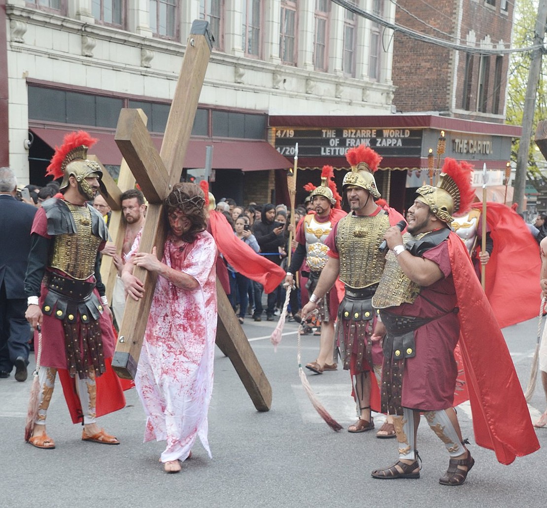 A bloody Jesus, wearing a crown of thorns, is burdened by the weight of the cross as he and his followers relive the Passion of Christ, from his condemnation by Pontius Pilate to his entombment.