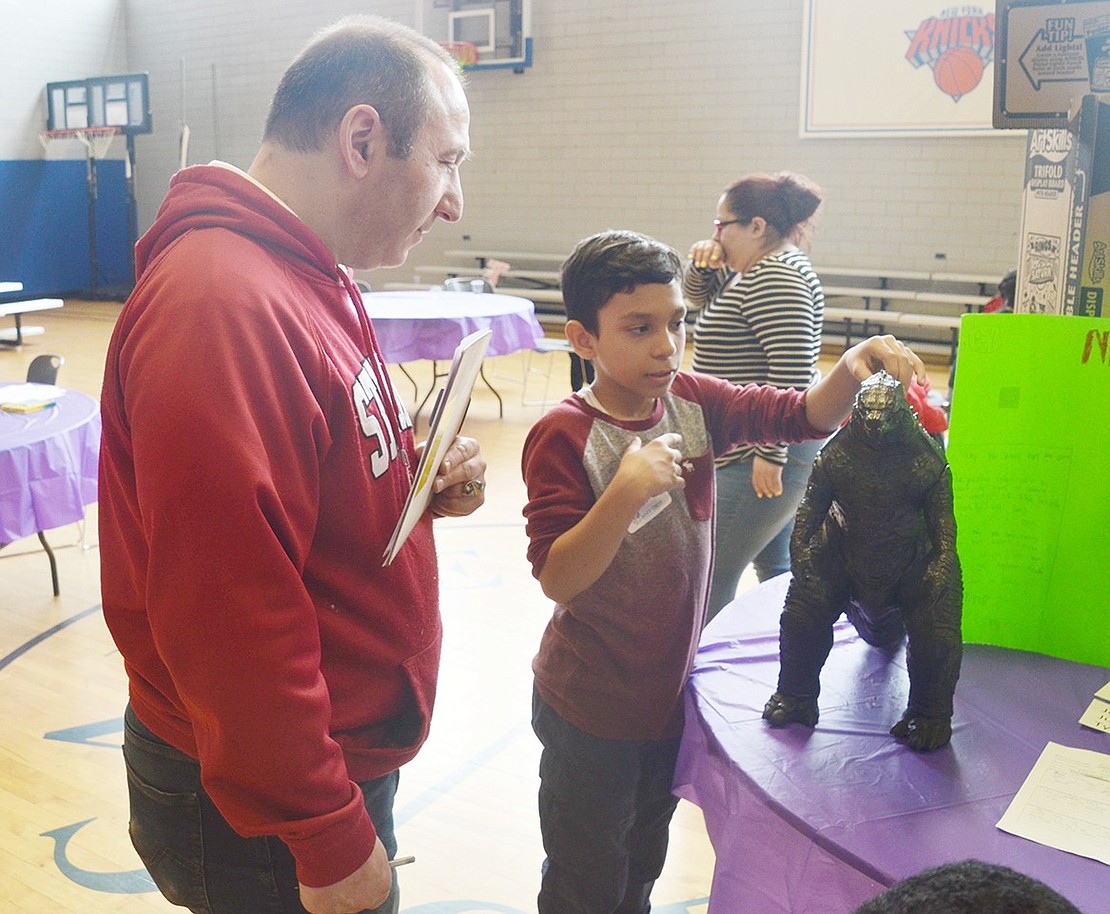 After designing a Godzilla video game and marketing plan with his friends, Edison School fifth-grader Tyler Beccerra describes the plot to Keith Kaplan with a monster figurine he brought for the display. Kaplan traveled from Ramsey, N.J., to be a judge at the convention.