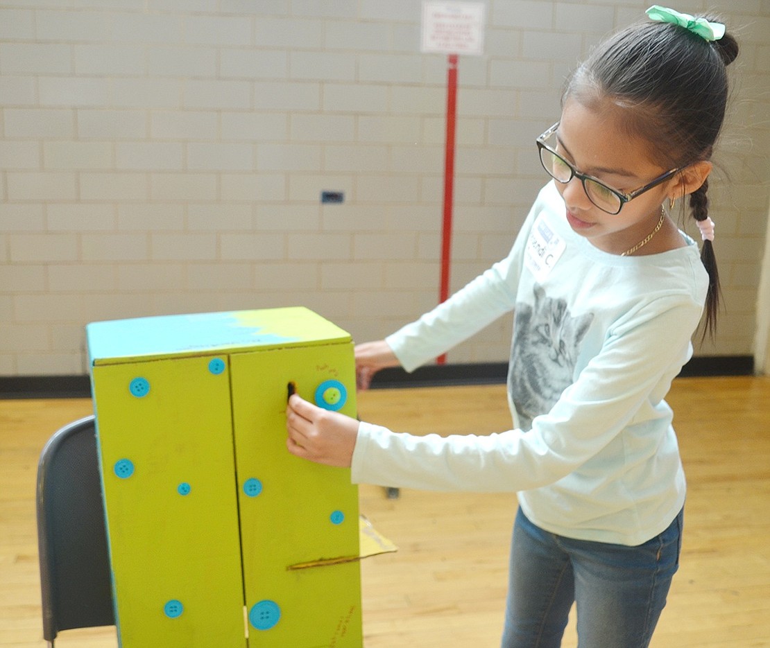 John F. Kennedy School fourth-grader Resendi Carrillo puts a coin into a box she made from cardboard that magically turns jars of slime into different colors. At the end of the day, Carrillo said she’s donating the change collected with the trick to the Carver Center.