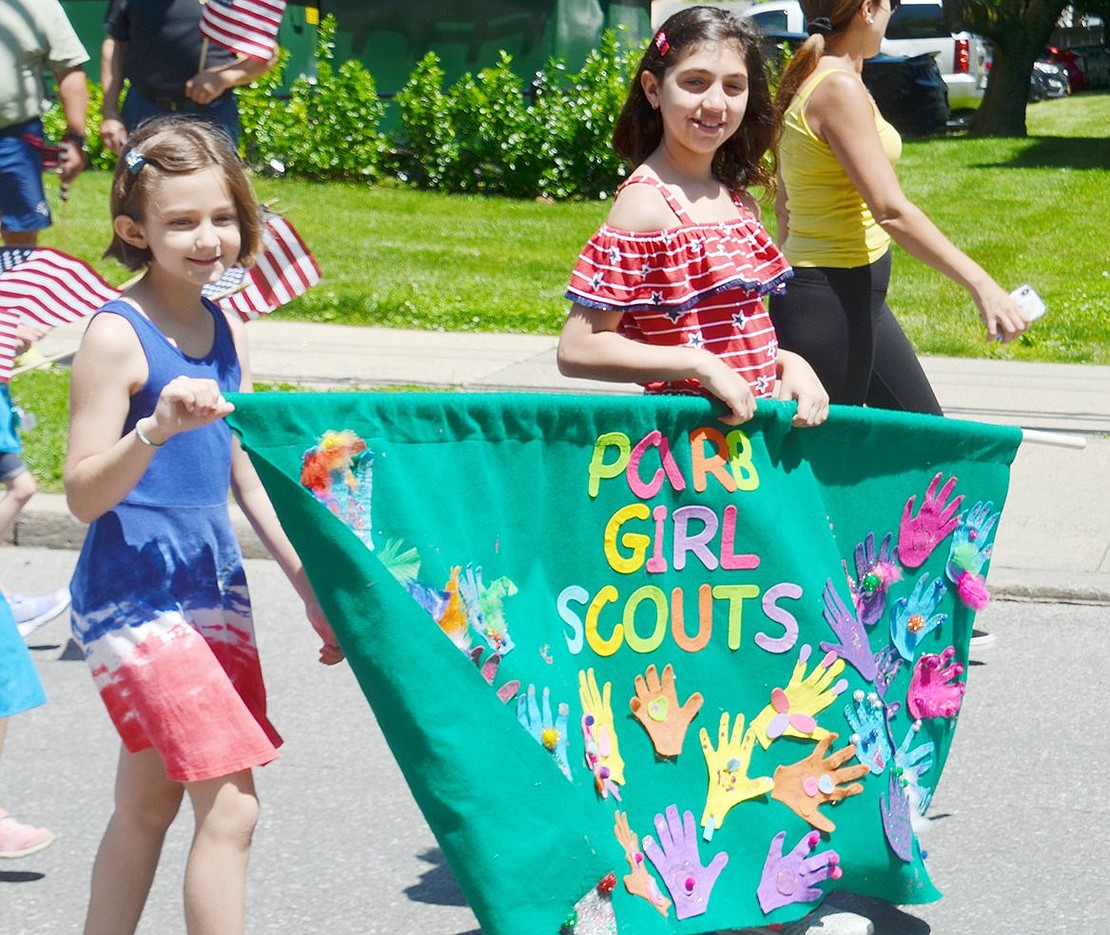 Proud to be doing their part in honoring lost soldiers, 9-year-old Port Chester residents Brooke Muto (left) and Megan Johnson carry a banner to lead fellow Port Chester/Rye Brook Girls Scouts from various other troops.