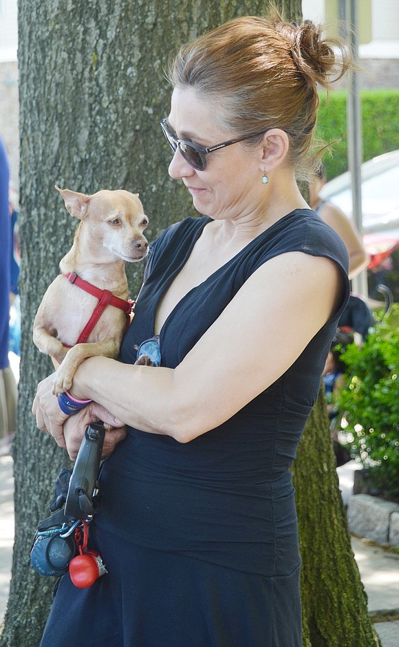 Soundview Street resident Lauren Castaneda stands on the corner of her road and Westchester Avenue to watch the procession go by. She comforts her dog, Cinnamon, who’s in full-body shakes from all the action.