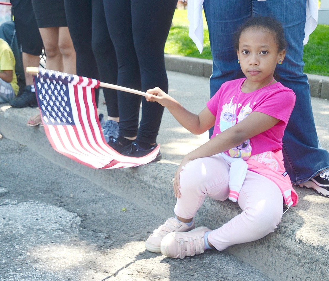 Sitting with the best view on the curb outside the former Our Lady of Mercy Church, John F. Kennedy School 7-year-old Stephanie Richardson waves an American flag as the parade strolls through.