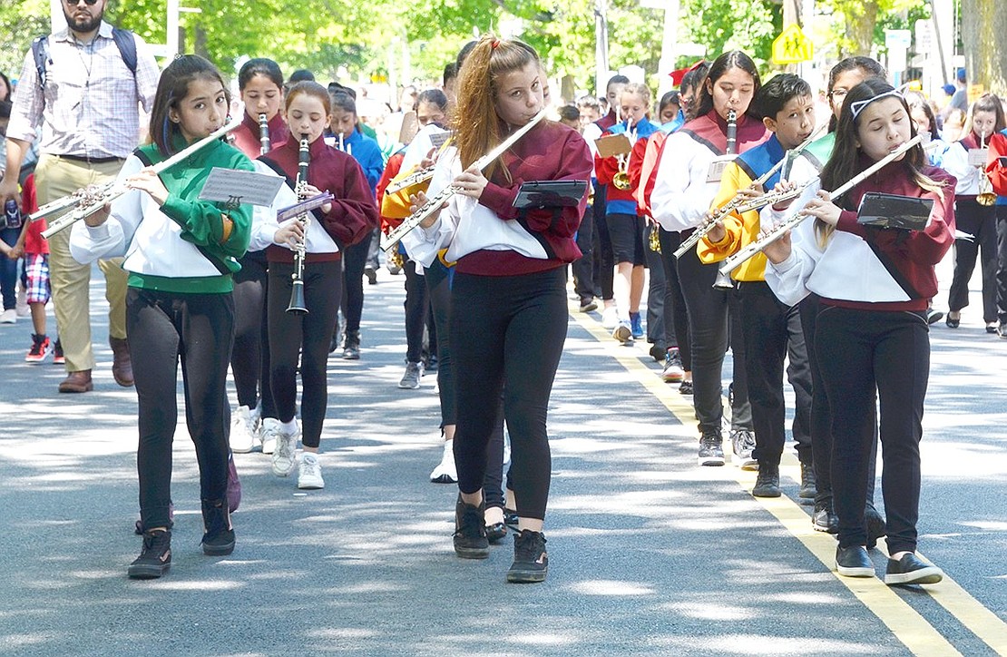 Near the library, three fifth-grade flutists from Edison School and King Street School lead their classmates in a mixed elementary school band ensemble down Westchester Avenue. From the left: Andrea Barajas, Sofia Rinello and Scarlett Pimentel.