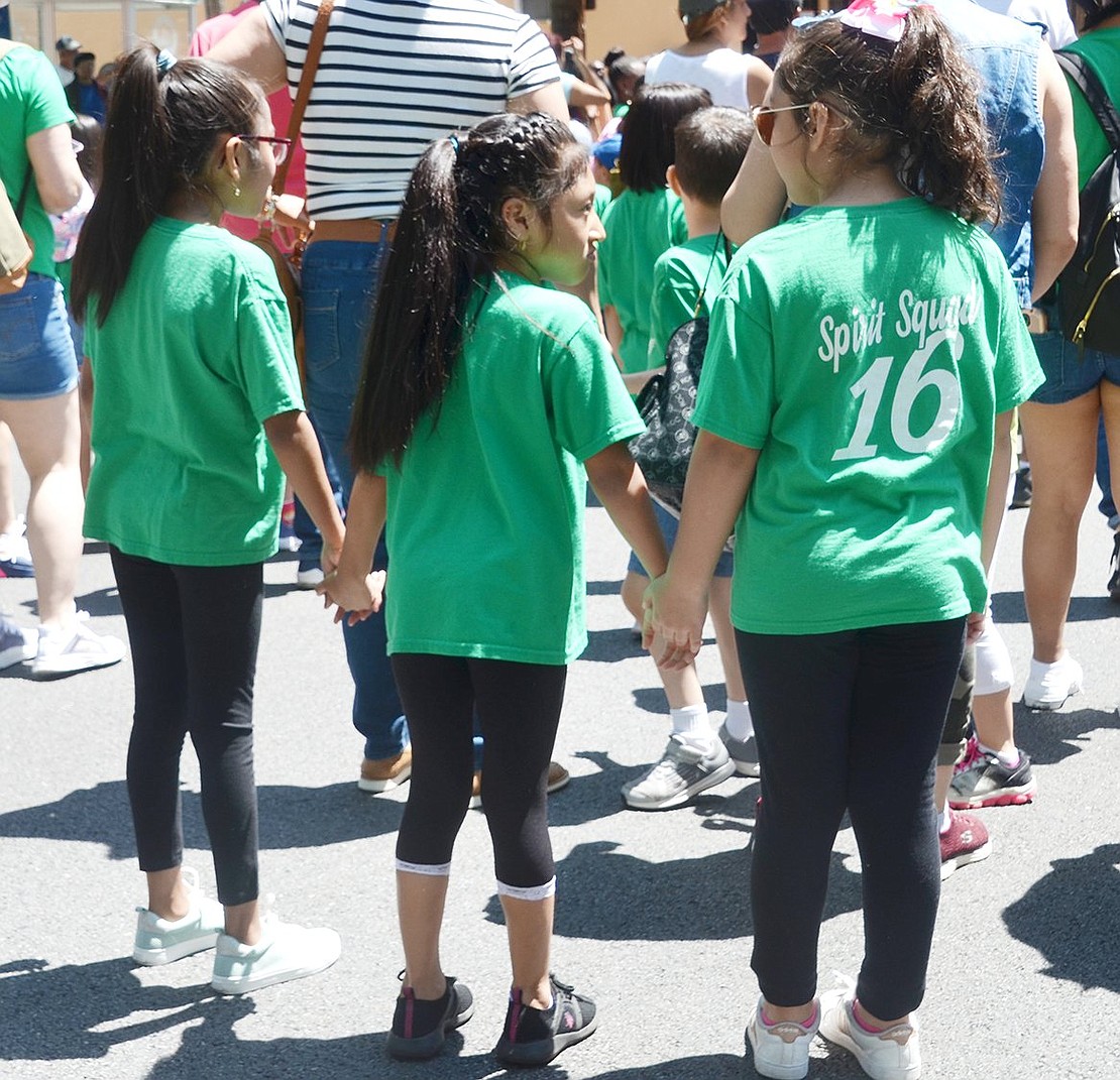 Edison School second-graders Jamie Pulla (left), Camilla Sigua and Marianna Cruz hold hands as they close out of the procession.
