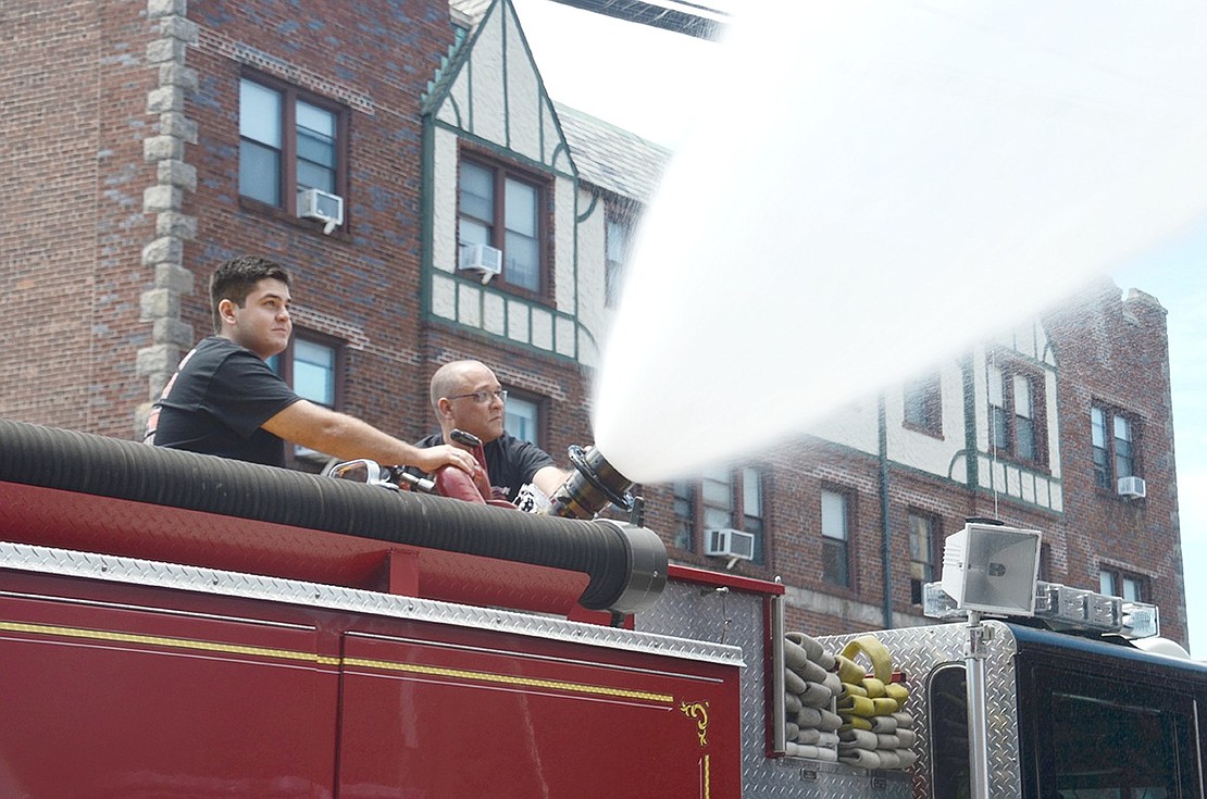 Harry Howard Engine & Hose firefighter Leonardo D’Alessandro (left) and Reliance Engine & Hose firefighter Pietro Goes blast water from the top of an old Port Chester Fire Department fire truck to shower the department’s two new rigs (click right). The community celebrated the arrival and blessing of the new trucks with a traditional Wet Down at Fire Headquarters on Westchester Avenue on Saturday, June 15.