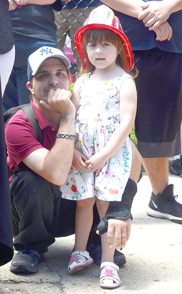 Frank Russo kneels down to watch the blessing ceremony with his 3-year-old daughter Madison, who sports a fashionable plastic firefighter hat. The Greenwich residents took interest in the Wet Down because Frank is a former Explorer with the Port Chester Fire Department.